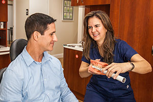 A dental assistant demonstrates proper brushing techniques to a patient.