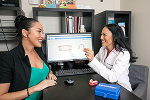 Dr. Johnson shows a patient a clear invlisalign aligner during a consultation.