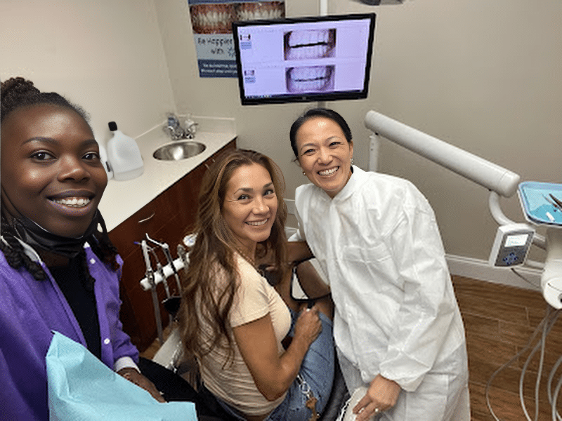 Dr. Charmaine Johnson smiling next to patient and staff at FL dental clinic