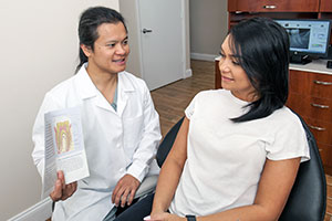 Dr. Bui shows a patient a diagram of the tooth root canal structure.