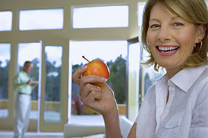 All-On-Four woman smiling as she holds an apple.,